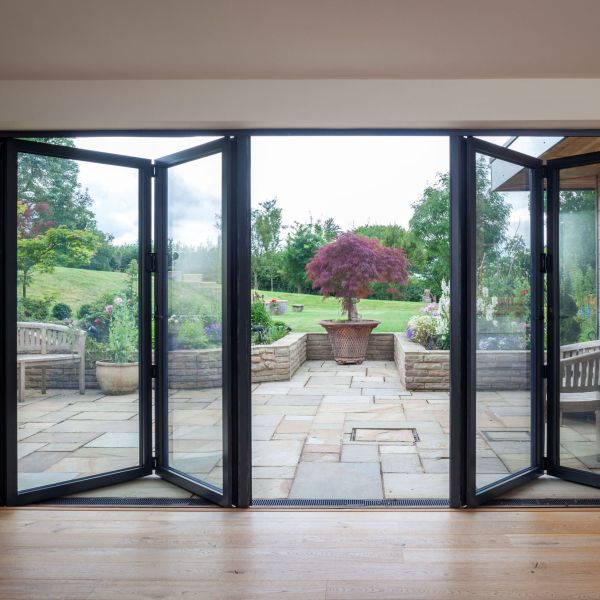 PANORAMA aluminium bi-fold doors creating a wide opening between a home and garden. PANORAMA aluminium bi-fold doors creating a wide opening between a home and garden.